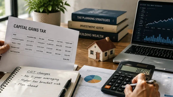 Investor reviewing capital gains tax documents beside a calculator, house model and laptop on a timber desk.
