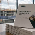 HIA policy submission on a desk with a blurred construction site behind it, representing the housing industry’s warning on investor tax changes and supply risks.