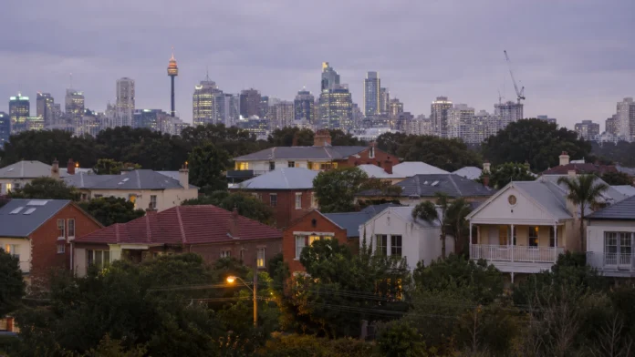 Sydney housing skyline at dusk, with suburban homes in the foreground and high-rise buildings in the distance, reflecting a cautious Australian property market outlook.