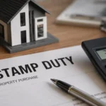 A premium desk scene showing a stamp duty property purchase document, calculator and small house model, representing Queensland property tax pressure and investor policy risk.